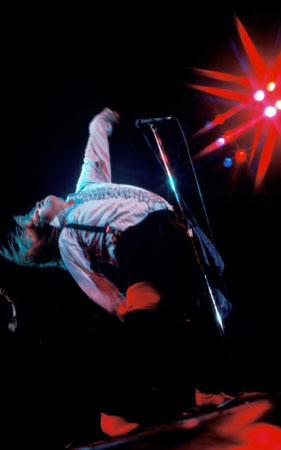 archive photo of Meat Loaf performing live, his back arched so that his face points to the ceiling while his feet are planted on the floor