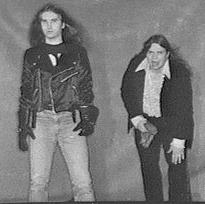 Jim Steinman (left, standing in foreground) and Meat Loaf (right, hunched over as if pained)
